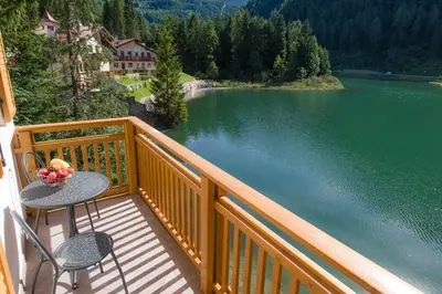 a balcony with a table and chairs next to a lake at Villa Edelweiss in Alleghe
