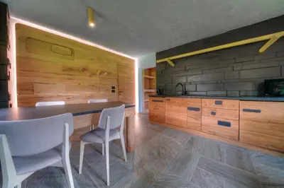 a kitchen with wooden cabinets and a table and chairs at Tana del Picchio in Falcade