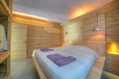 a bedroom with a bed in a wooden wall at Tana del Picchio in Falcade