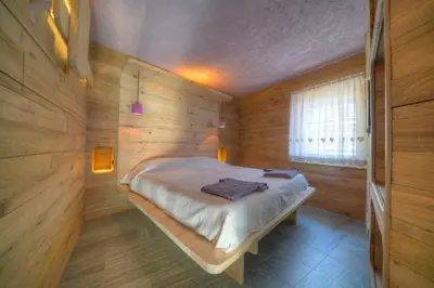 a bedroom with a bed in a wooden room at Tana del Picchio in Falcade