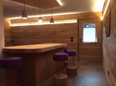 a kitchen with a bar with purple stools at Tana del Picchio in Falcade