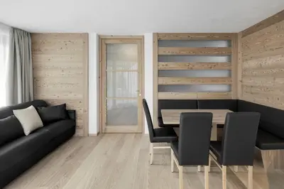 a dining room with a black couch and a table at Ciasa Sunara in Colfosco