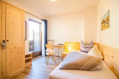 a bedroom with a bed and a desk and a window at Garni Stübele in Tirolo