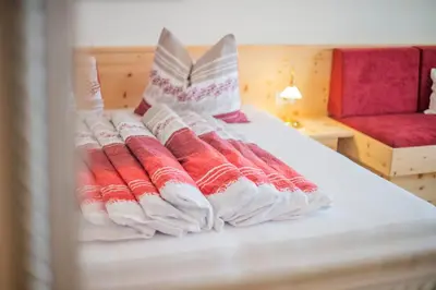 a bed with red and white pillows on it at Garni Stübele in Tirolo