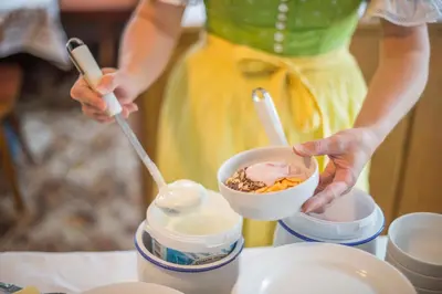 a woman in a yellow dress holding a bowl of food at Garni Stübele in Tirolo