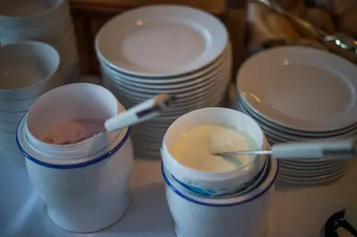 two styrofoam cups with a spoon in it next to plates at Garni Stübele in Tirolo