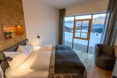 a bedroom with a bed and a large window at Mair am Anger-Appartments in Riscone