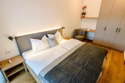 a bedroom with a large bed with white pillows at Mair am Anger-Appartments in Riscone