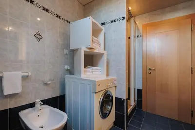 a bathroom with a washing machine and a sink at Alpenvilla Large Family Apartment - by Familiaris- Pools 500 meters in Valdaora