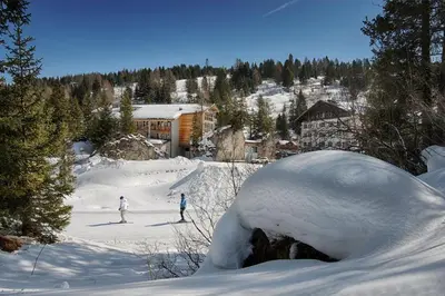a couple of people skiing down a snow covered slope at Hotel Garni Elisir in Arabba
