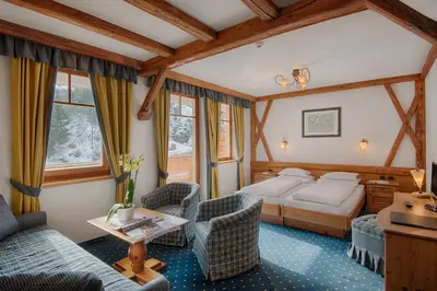 a hotel room with a bed and two chairs at Hotel Garni Elisir in Arabba