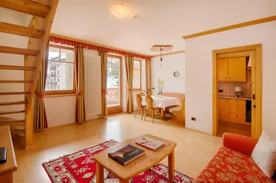 a living room with a table and a kitchen at Hotel Garni Elisir in Arabba