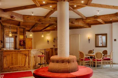 a room with a column and a table with chairs at Hotel Garni Elisir in Arabba