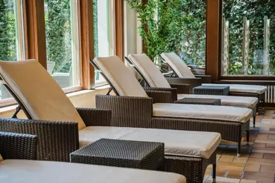 a row of chairs and tables in a room with windows at NaturResidence Dolomitenhof in Siusi