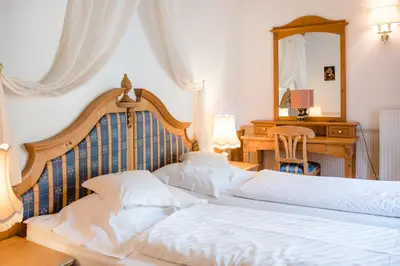 two beds in a bedroom with a desk and a mirror at NaturResidence Dolomitenhof in Siusi