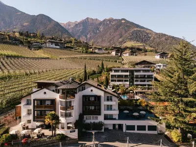 a house in a vineyard with mountains in the background at Appartement KroneLiving in Tirolo