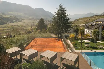 a tennis court with chairs and a tennis courtourt at Appartement KroneLiving in Tirolo