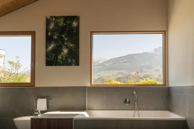 a bath tub in a bathroom with two windows at Appartement KroneLiving in Tirolo
