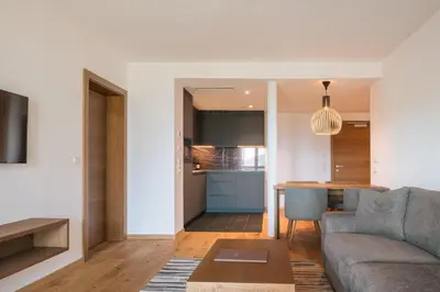 a living room and kitchen with a couch and a table at Appartement KroneLiving in Tirolo