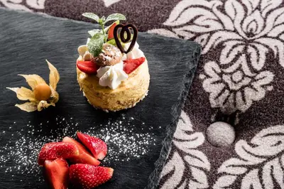 a dessert on a black plate with strawberries on it at Engels Park in Vipiteno