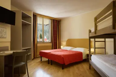 a bedroom with a bed and a desk and a bunk bed at Hotel Portavescovo in Arabba
