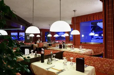 a restaurant with tables and chairs and chandeliers at Hotel Portavescovo in Arabba
