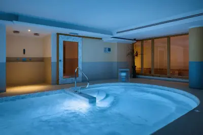 a jacuzzi tub in a room with a blue light at Hotel Portavescovo in Arabba