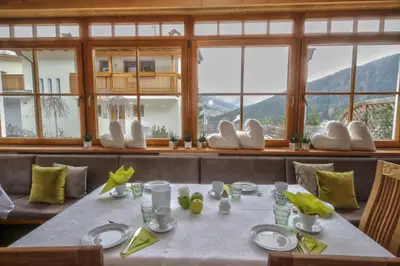 a dining room with a table with chairs and windows at Ciasa Montanara in La Villa