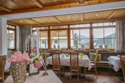 a dining room with tables and chairs and windows at Ciasa Montanara in La Villa