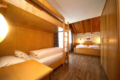 a bedroom with two bunk beds and a table at Ciasa Montanara in La Villa