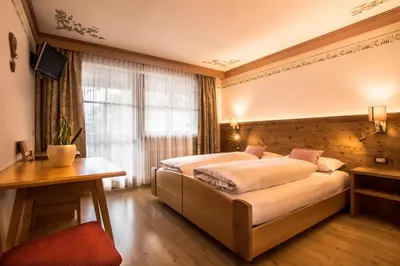 a bedroom with two beds and a desk and a window at Ciasa Montanara in La Villa
