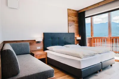 a bedroom with a bed and a couch and a window at Gasthof Hotel Wöhrmaurer in Feldthurns