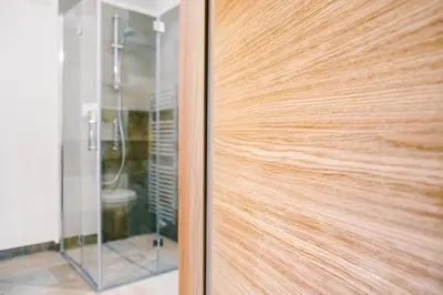 a wooden door in a bathroom with a shower at Gasthof Hotel Wöhrmaurer in Feldthurns