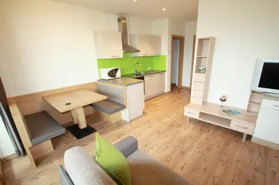 a living room with a kitchen with a table at Gasthof Hotel Wöhrmaurer in Feldthurns
