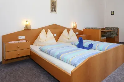 a bedroom with a large wooden bed with blue sheets at Gasthof Hotel Wöhrmaurer in Feldthurns