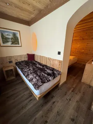 a bedroom with a bed in the corner of a room at Hotel Ciasa Lorenzi in Cortina dʼAmpezzo
