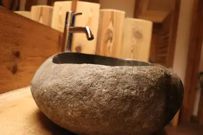a stone sink with a faucet on a table at Hotel Ciasa Lorenzi in Cortina dʼAmpezzo