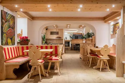 a restaurant with wooden tables and chairs and a kitchen at Hotel Ciasa Lorenzi in Cortina dʼAmpezzo