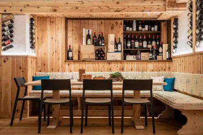 a restaurant with a bar with chairs and wine bottles at Hotel Ciasa Lorenzi in Cortina dʼAmpezzo