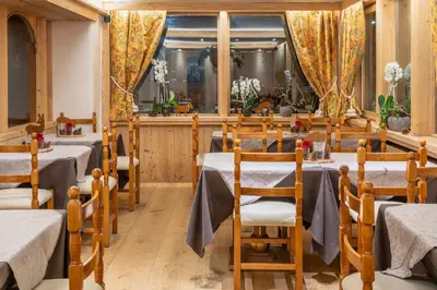 a restaurant with tables and chairs in a room at Hotel Ciasa Lorenzi in Cortina dʼAmpezzo