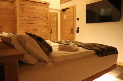 a bedroom with a bed with a television on the wall at Hotel Ciasa Lorenzi in Cortina dʼAmpezzo