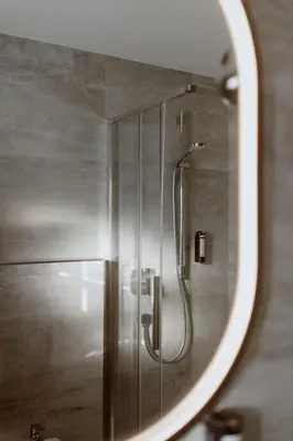 a mirror reflecting a shower in a bathroom at Garberhof Dolomit Family in Rasùn di Sotto