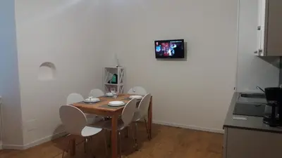 a dining room table with chairs and a television on a wall at La casa di Cì-CÌ in Merano