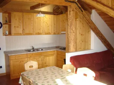 a kitchen with wooden cabinets and a sink and a table at Residenza Domino in Selva di Cadore