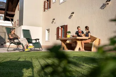 three women sitting at a table outside of a building at Apartments Heritage House Margherita in Santa Cristina in Val Gardena