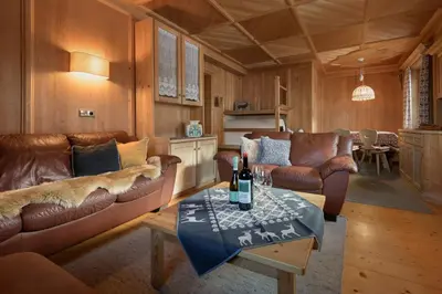 a living room with couches and a table with a bottle of wine at Apartments Heritage House Margherita in Santa Cristina in Val Gardena