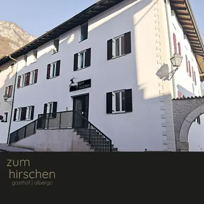a white building with black windows and a staircase at Gasthof Zum Hirschen Margreid in Magrè allʼ Adige