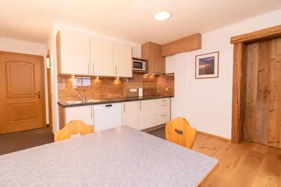 a kitchen with white cabinets and a table and chairs at Sennerhof in Racines