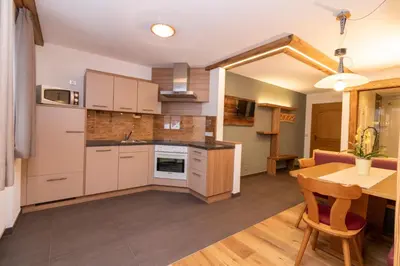 a kitchen with white cabinets and a table and a dining room at Sennerhof in Racines