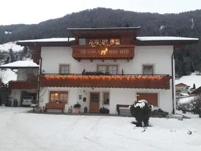 a large white building with a balcony in the snow at Sennerhof in Racines